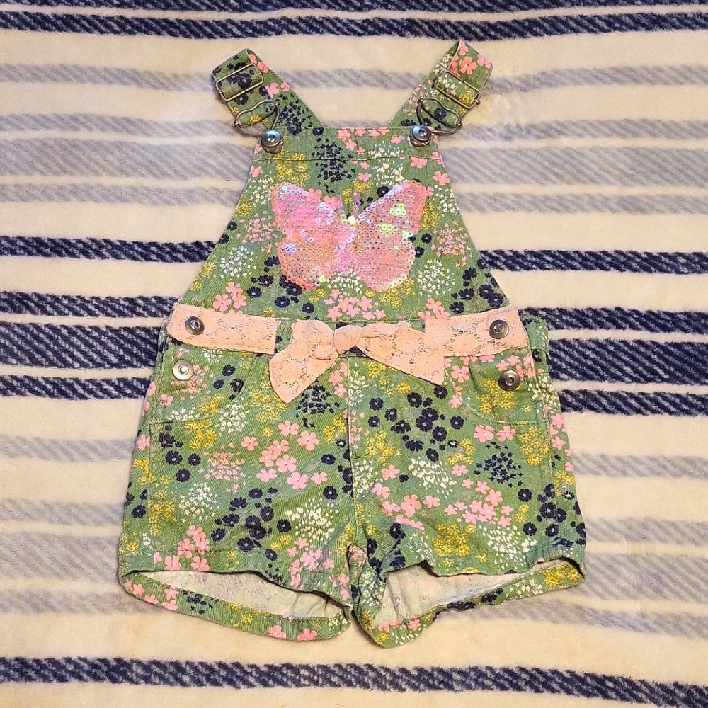 Green floral short bibs with sequin butterfly and pink lace belt details.
